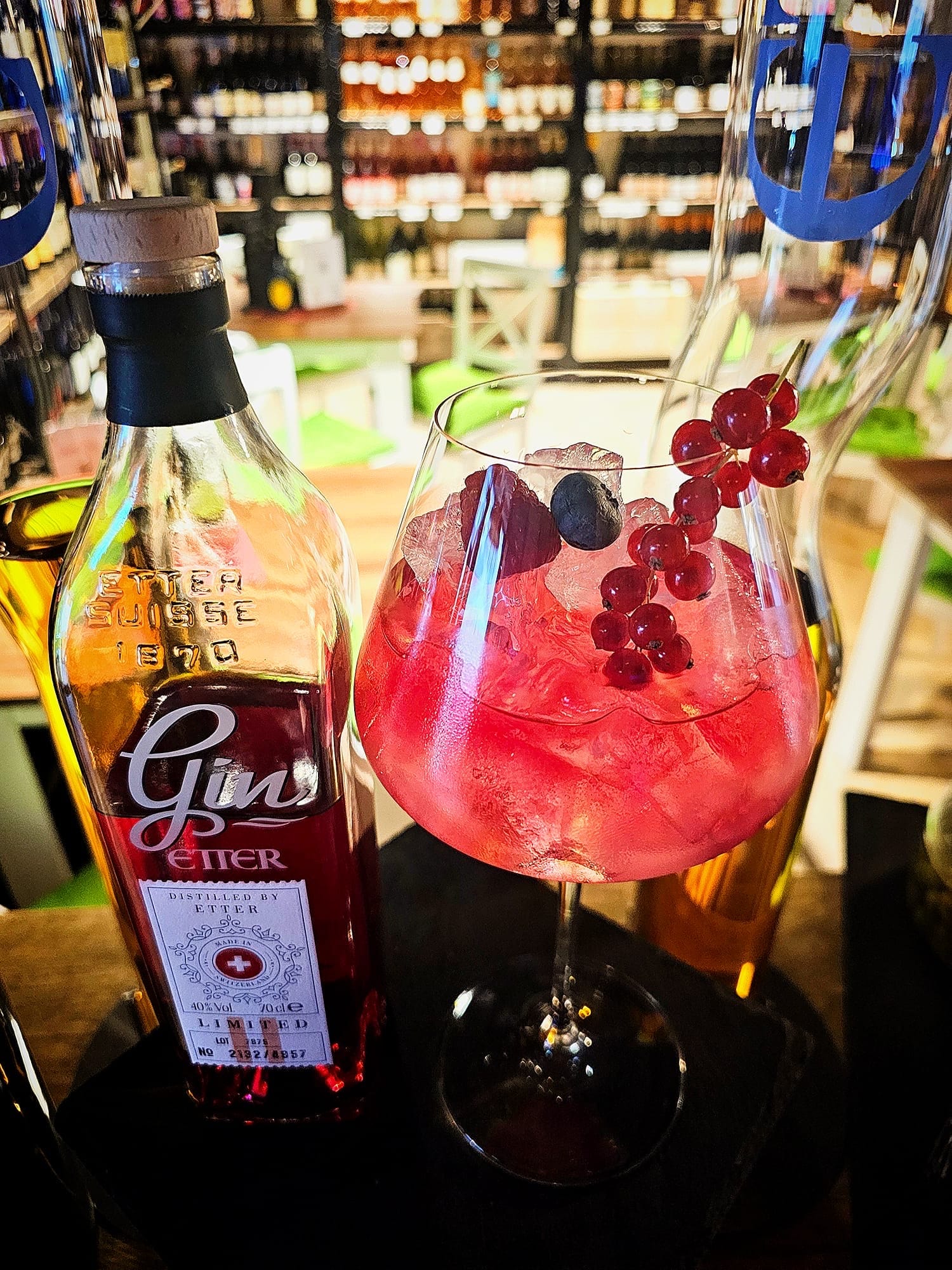 Gin Tonic mit Beeren neben einer Flasche Etter Gin Limited