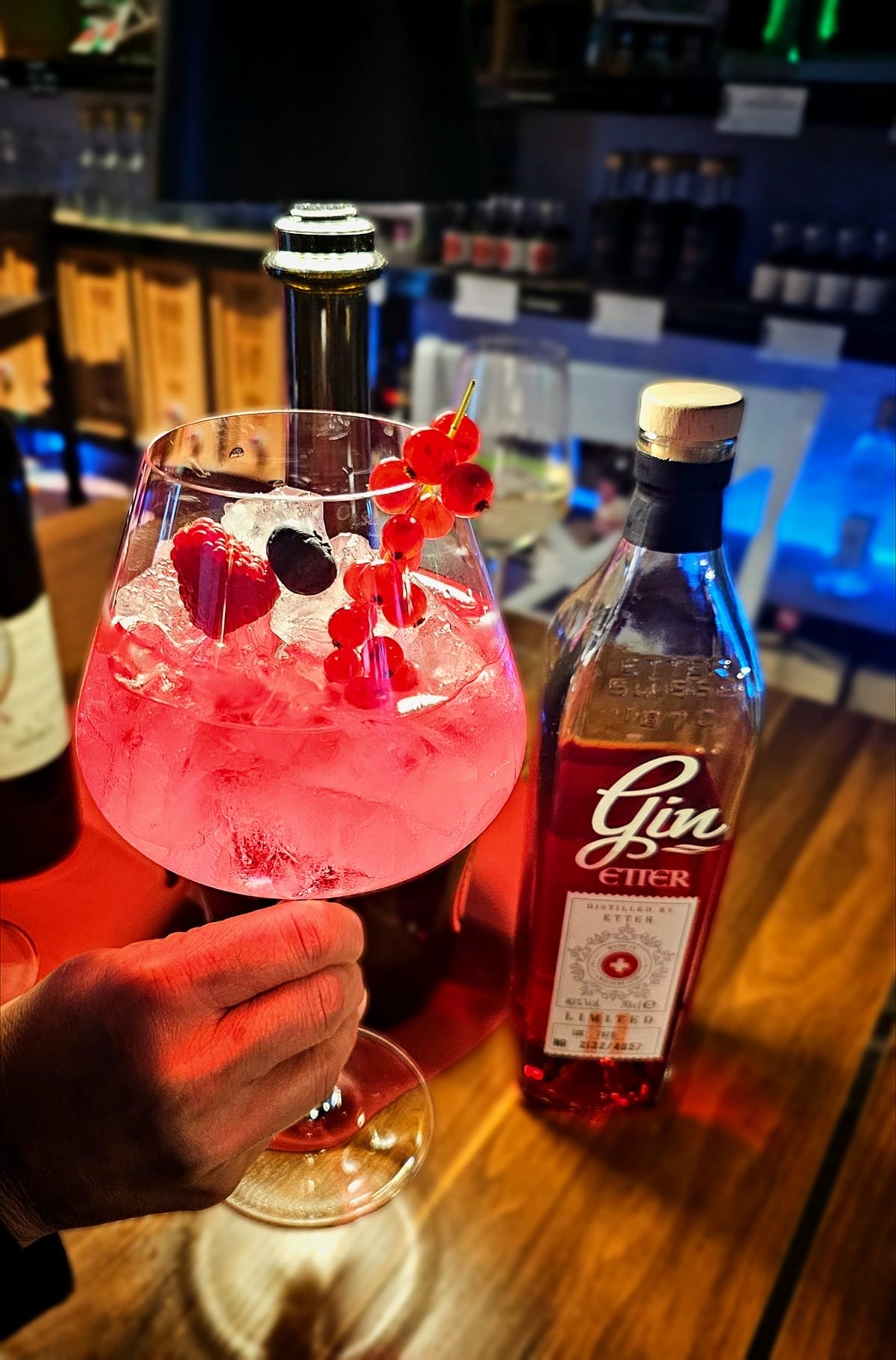 Gin Tonic mit Beeren und eine Flasche Etter Gin Limited am Tresen der Weinbar