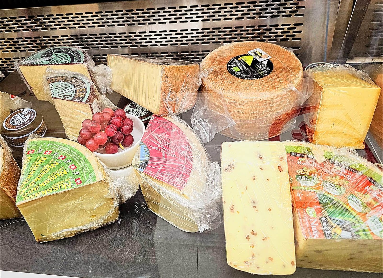 Käsetheke mit Hartkäse-Laiben und Trauben in der Weinbar